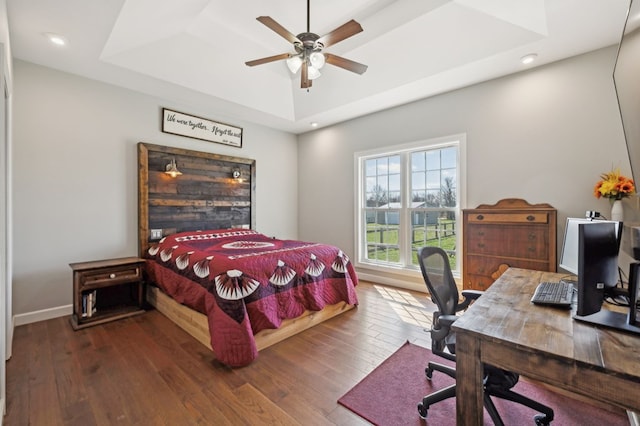 bedroom featuring ceiling fan, recessed lighting, baseboards, wood-type flooring, and a raised ceiling