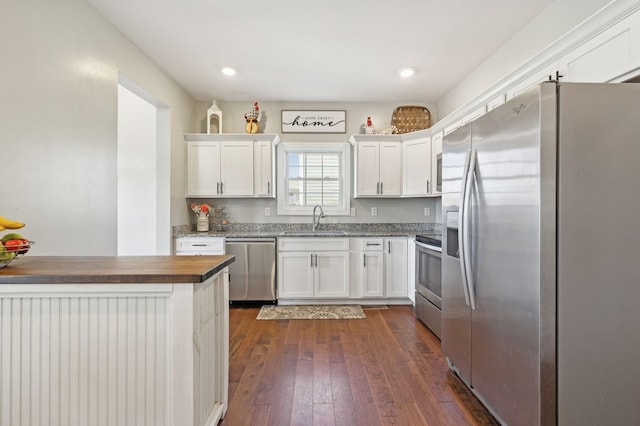 kitchen with dark wood finished floors, stainless steel appliances, recessed lighting, white cabinets, and a sink