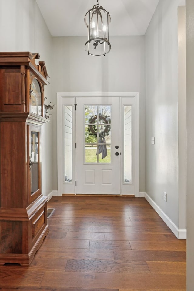 entrance foyer with a chandelier, wood-type flooring, and baseboards