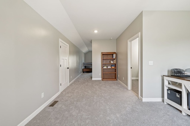 hallway featuring baseboards, visible vents, and light colored carpet