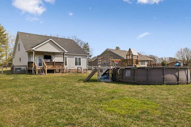 back of property with a deck, a lawn, fence, and an outdoor pool