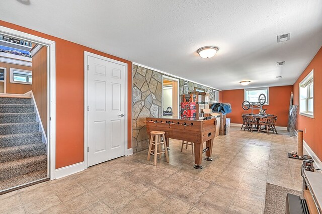 rec room featuring visible vents, a textured ceiling, and baseboards