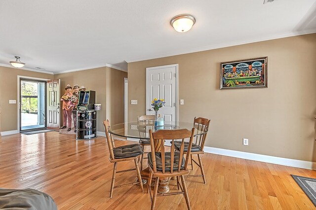 dining area with light wood finished floors, crown molding, and baseboards