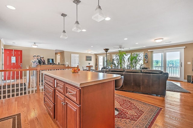 kitchen with a kitchen island, crown molding, pendant lighting, light wood-type flooring, and brown cabinets