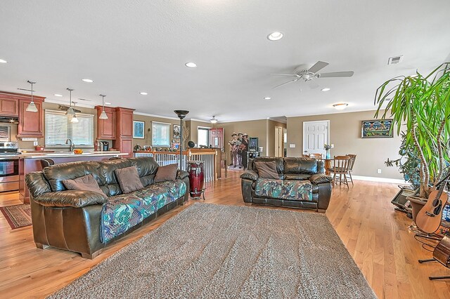 living room with visible vents, ceiling fan, light wood-type flooring, and baseboards