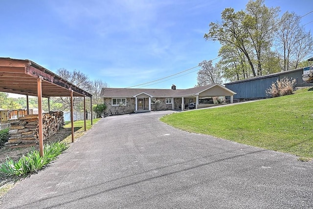 view of front facade with aphalt driveway, stone siding, and a front lawn