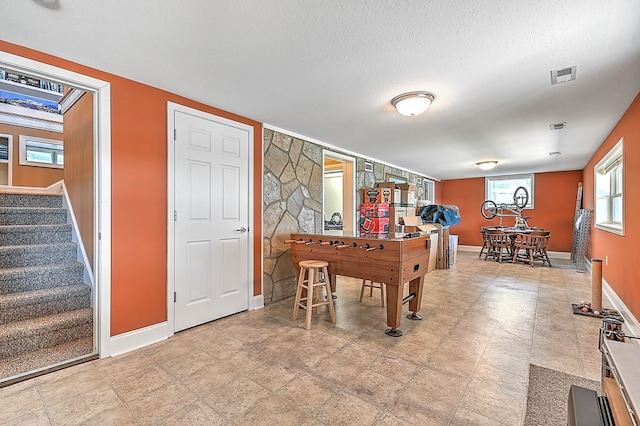 recreation room with visible vents, baseboards, and a textured ceiling