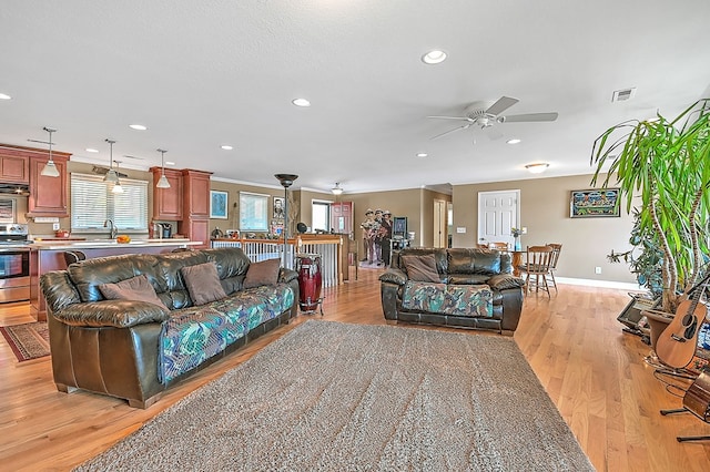 living room featuring ceiling fan, baseboards, visible vents, and light wood-type flooring