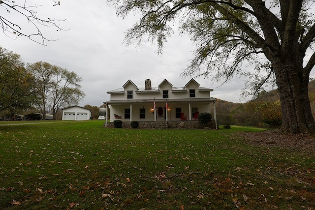 view of front of home with a front yard, covered porch, a detached garage, and a chimney