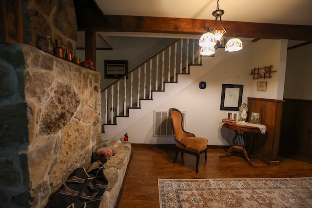 interior space with a chandelier, wainscoting, wood finished floors, and beam ceiling