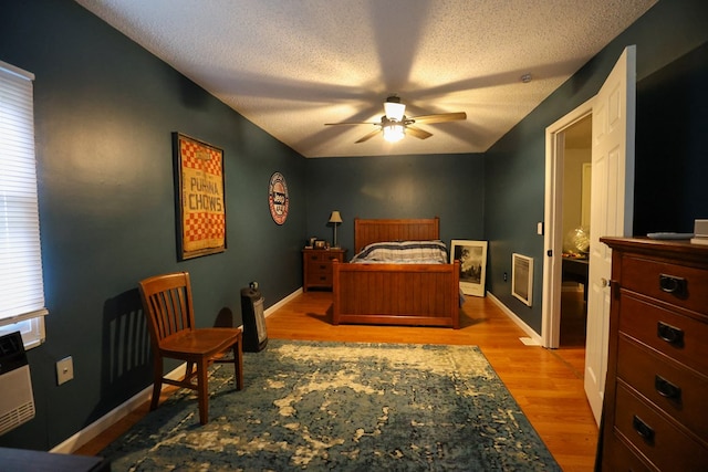 bedroom featuring baseboards, ceiling fan, a textured ceiling, and light wood finished floors