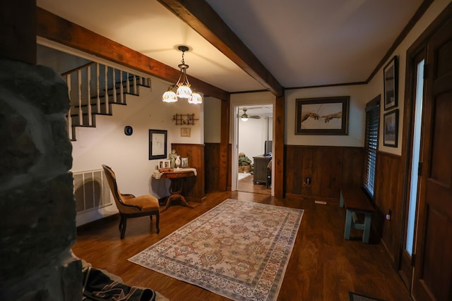 foyer entrance with a wainscoted wall, wooden walls, and beam ceiling