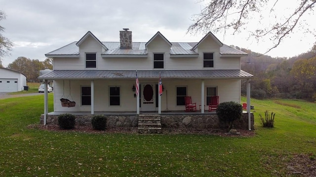 view of front of home with a front yard, covered porch, metal roof, and a chimney