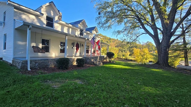 view of side of property with covered porch and a lawn