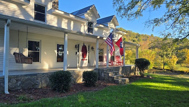 view of side of property with a porch, a yard, and metal roof