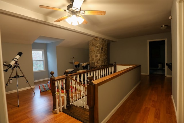 hall with lofted ceiling with beams, wood finished floors, an upstairs landing, and baseboards