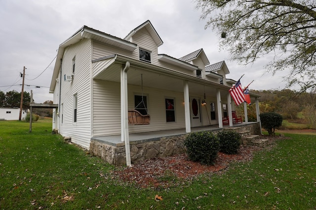 view of front of home with a porch, a front yard, and metal roof