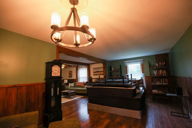 living room with a chandelier, dark wood finished floors, a wainscoted wall, and wood walls