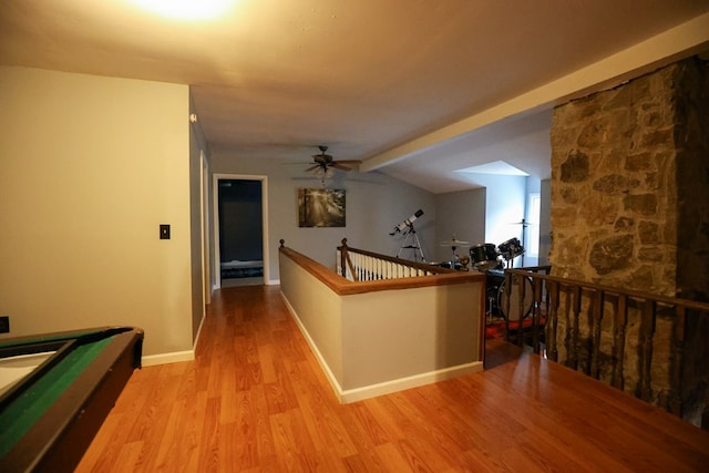 hallway with baseboards, vaulted ceiling with beams, light wood finished floors, and an upstairs landing