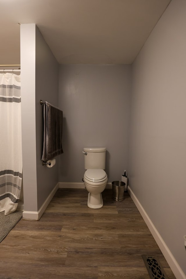 full bath featuring a shower with curtain, wood finished floors, toilet, and baseboards