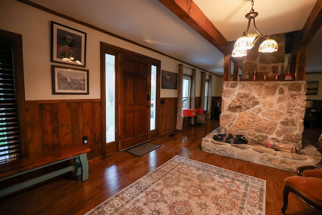 foyer entrance featuring dark wood-style floors, ornamental molding, wainscoting, wood walls, and beamed ceiling