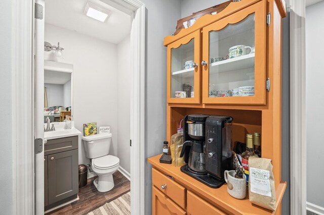 bathroom with toilet, baseboards, wood finished floors, and vanity