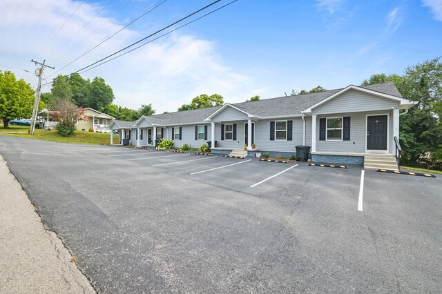 view of front of home with uncovered parking and roof with shingles