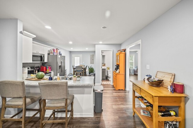 kitchen featuring white cabinets, appliances with stainless steel finishes, a breakfast bar, a peninsula, and light countertops