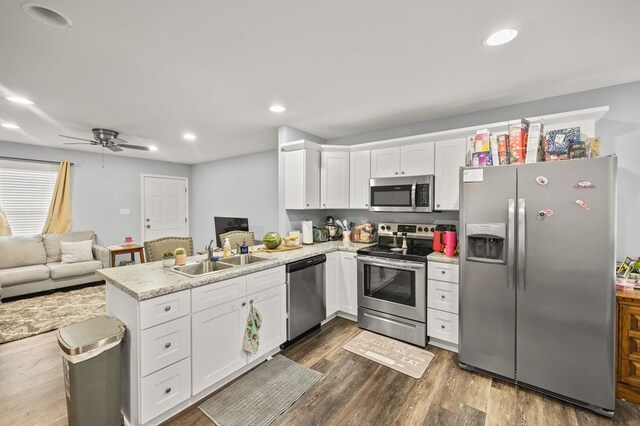 kitchen featuring stainless steel appliances, white cabinets, a sink, and a peninsula