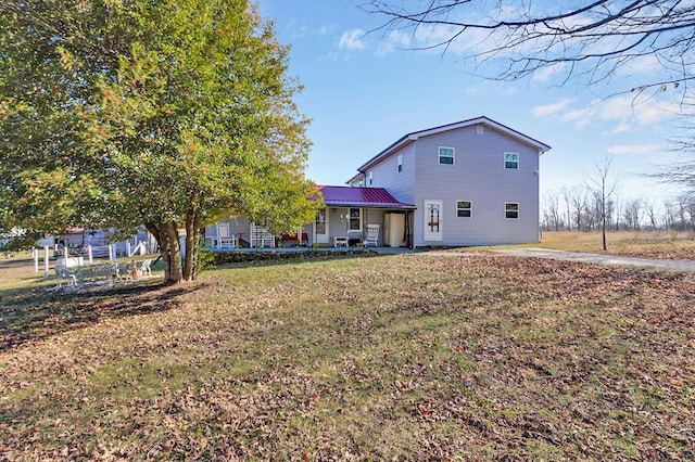 rear view of property featuring metal roof, a yard, and a porch