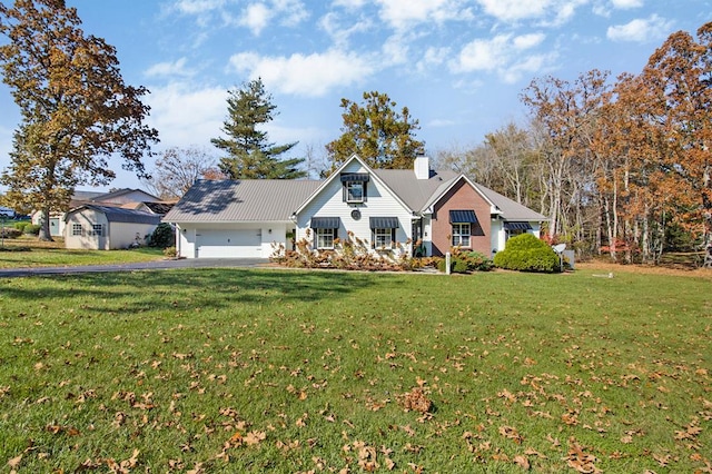 view of front of house with a front lawn, a chimney, an attached garage, and aphalt driveway