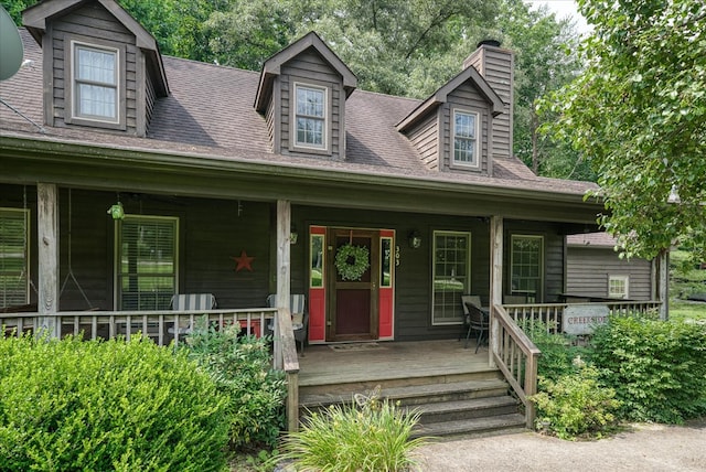 cape cod-style house with a porch, a chimney, and a shingled roof