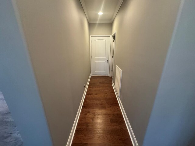 hallway with ornamental molding, baseboards, and dark wood-style flooring