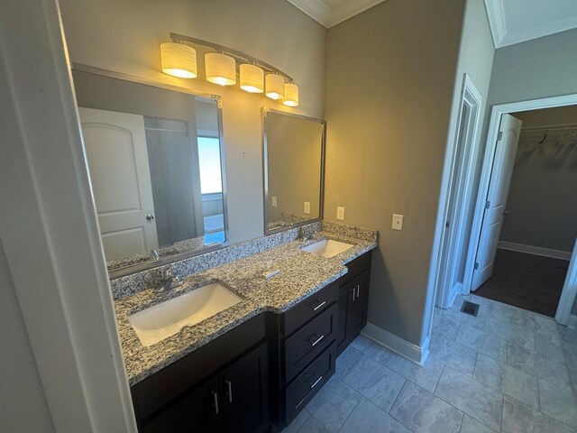 bathroom featuring a sink, baseboards, ornamental molding, and double vanity