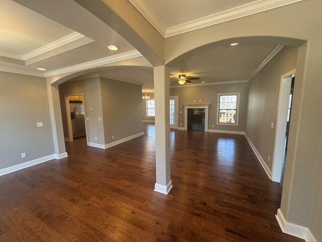 unfurnished living room featuring crown molding, baseboards, ceiling fan, dark wood finished floors, and a fireplace