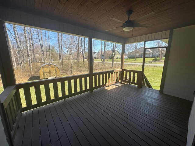 deck featuring an outbuilding, a lawn, a ceiling fan, a storage shed, and a lanai