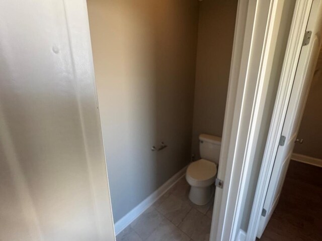 bathroom with tile patterned floors, toilet, and baseboards