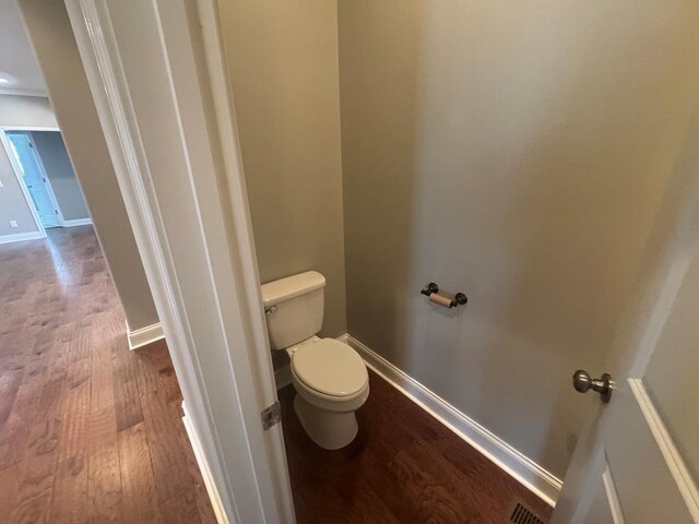 bathroom featuring toilet, wood finished floors, and baseboards