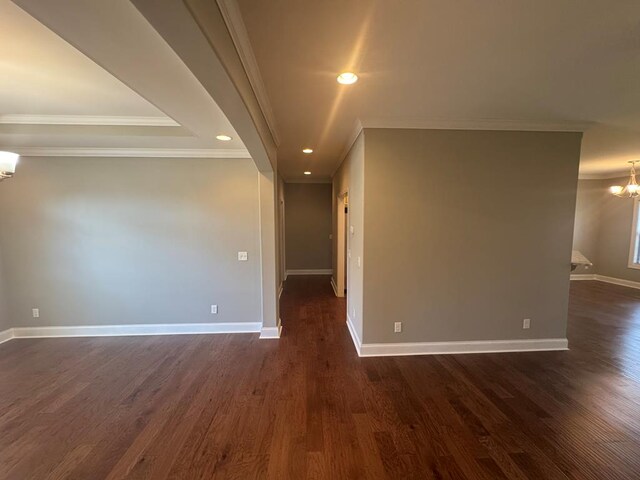 empty room with an inviting chandelier, a raised ceiling, baseboards, and dark wood-style flooring