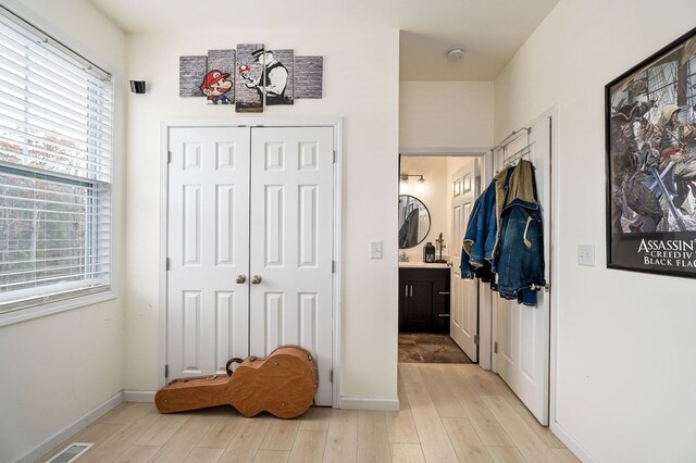 corridor with a healthy amount of sunlight, light wood-style floors, baseboards, and visible vents