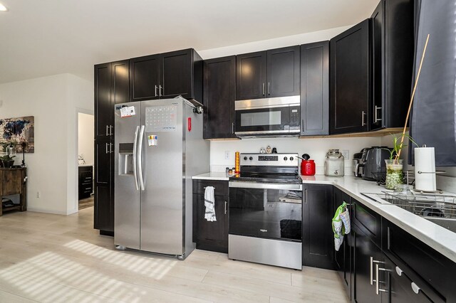 kitchen featuring appliances with stainless steel finishes, light countertops, and dark cabinets