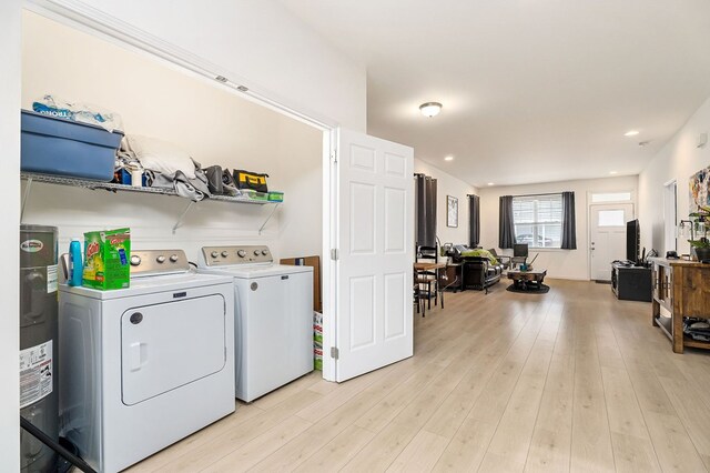 laundry room with electric water heater, laundry area, independent washer and dryer, and light wood-style flooring