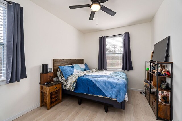 bedroom featuring light wood finished floors, a ceiling fan, and baseboards