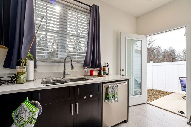 kitchen featuring light countertops, stainless steel dishwasher, a sink, and dark brown cabinetry