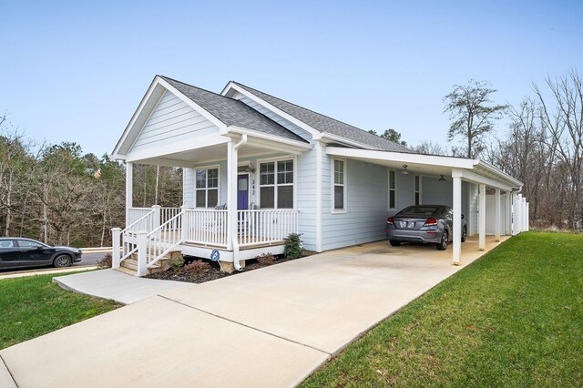 view of front of house featuring roof with shingles, covered porch, a front yard, a carport, and driveway