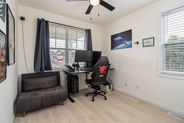 office space with light wood finished floors, baseboards, visible vents, and a ceiling fan