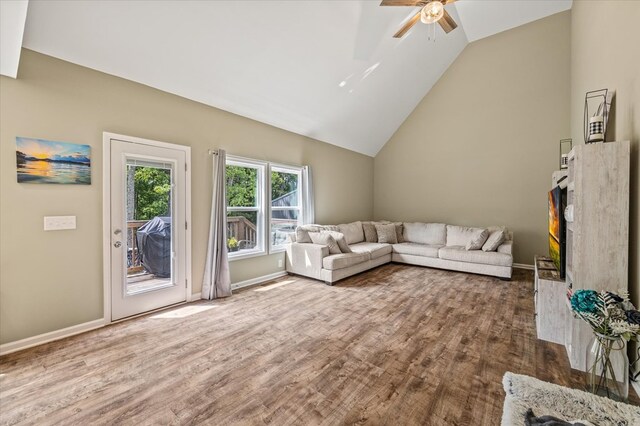 unfurnished living room with vaulted ceiling, ceiling fan, wood finished floors, and baseboards