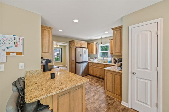 kitchen featuring a breakfast bar, decorative light fixtures, a peninsula, light stone countertops, and freestanding refrigerator