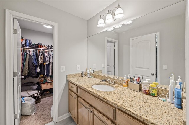 bathroom with a spacious closet, baseboards, and vanity