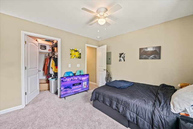 bedroom featuring light colored carpet, a ceiling fan, baseboards, a closet, and electric panel